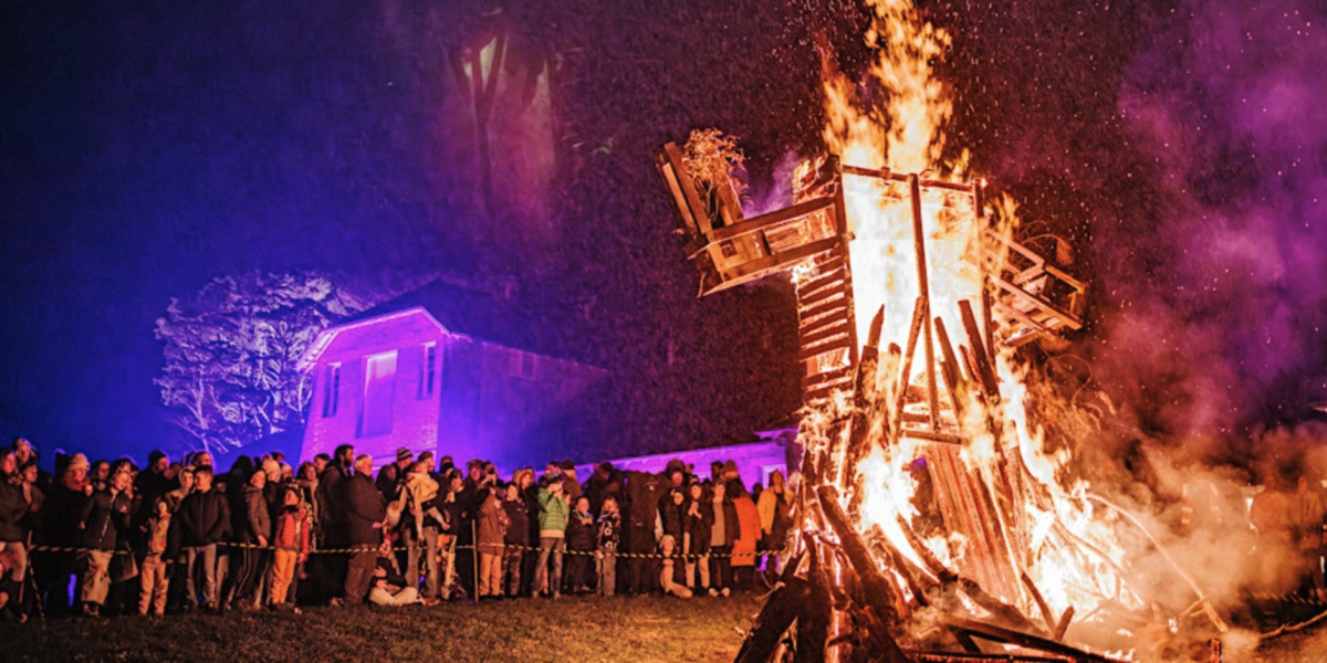 People watch wooden effigy of a person burn